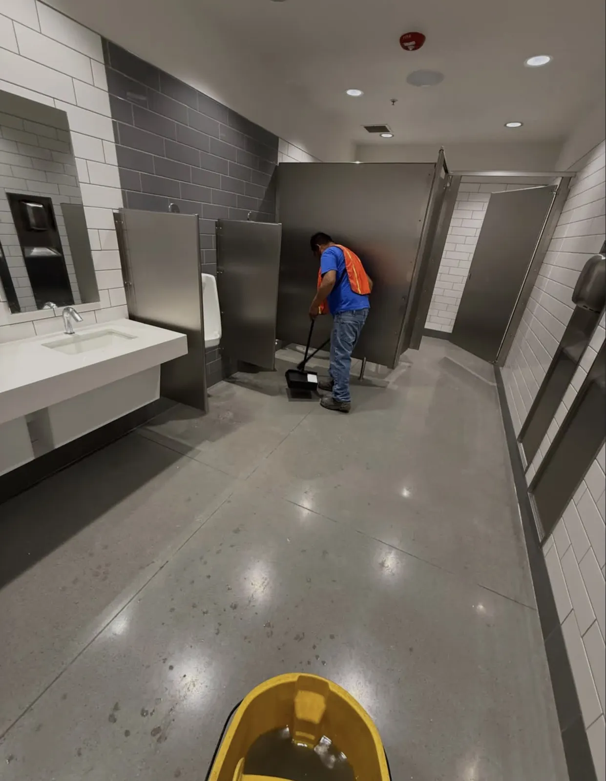 J&A cleaner sweeping a newly completed restroom